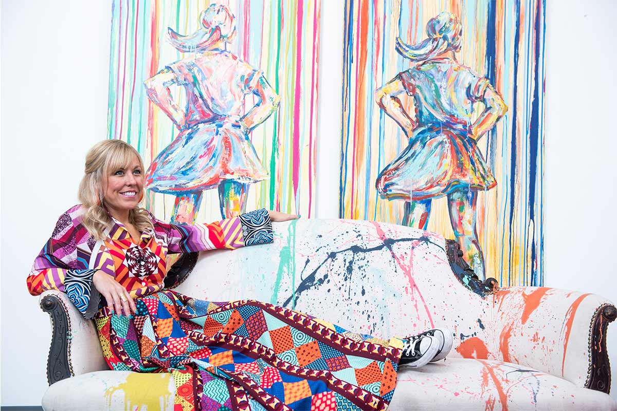 maggie o'neill in front of two of her paintings