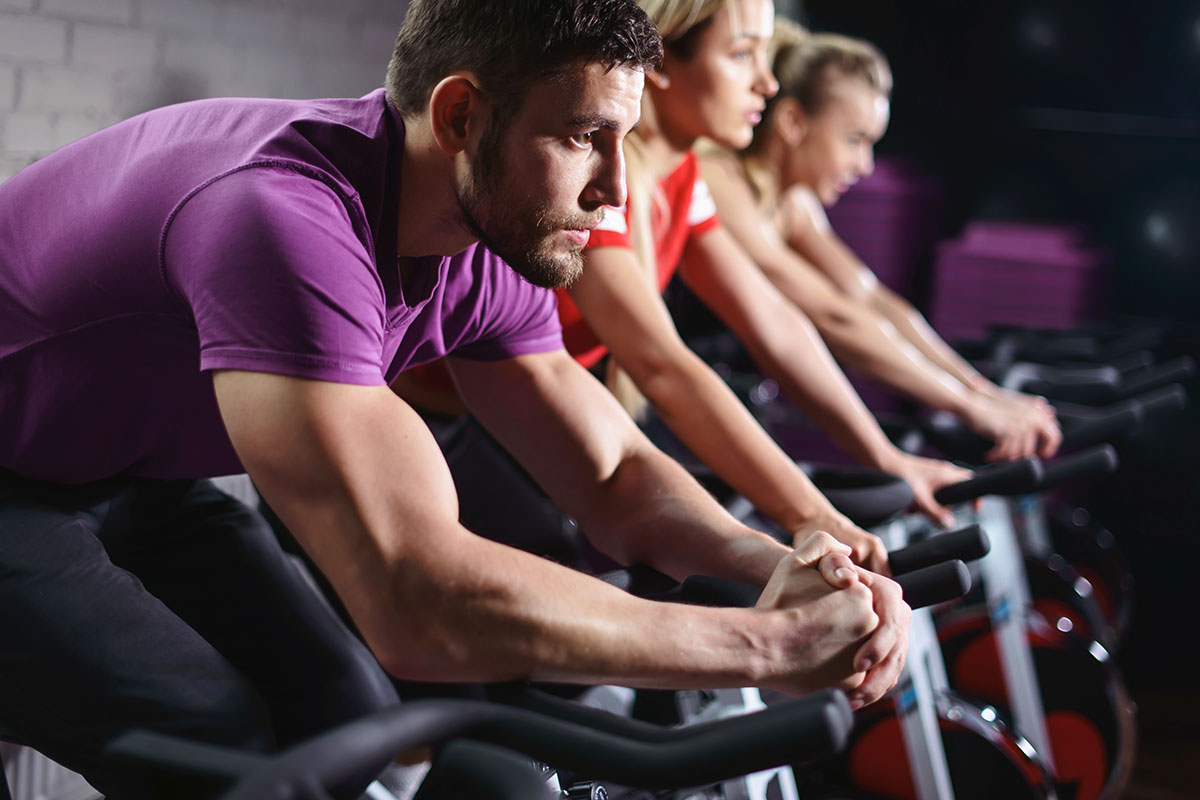 man on stationary fitness bike with purple shirt