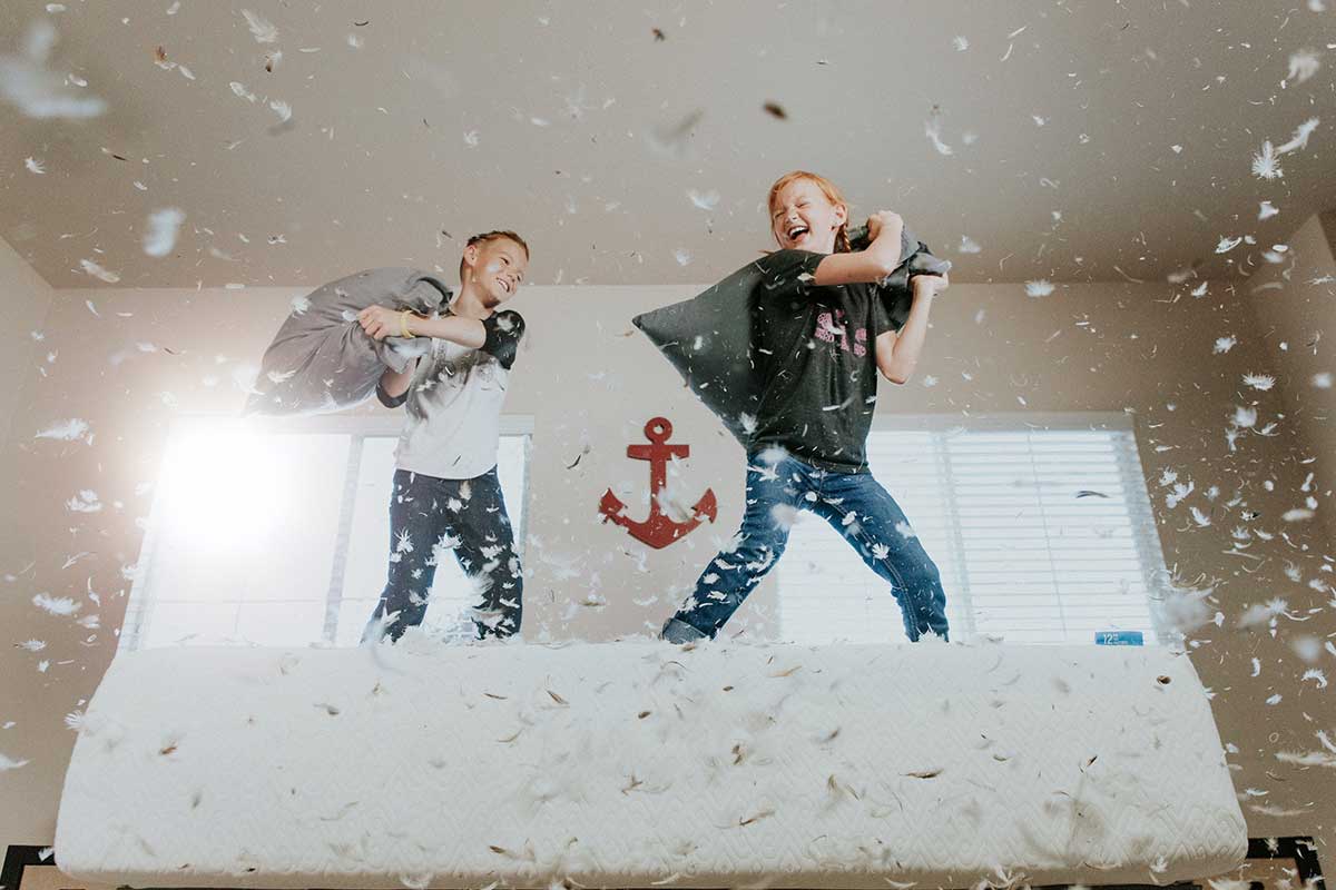 two boys having a pillow fight with feathers everywhere