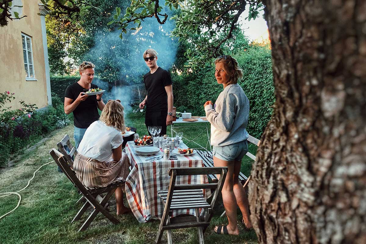 friends outside of house in backyard with table and chairs and food