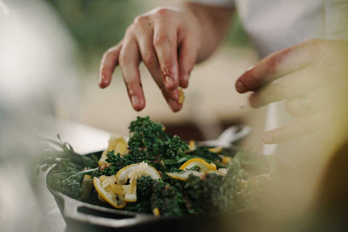 hands over pan with kale and lemons
