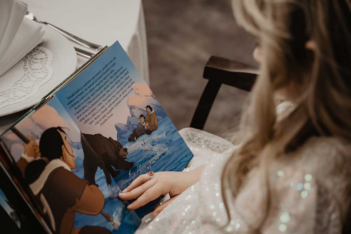 little girl with blonde hair reading disney book