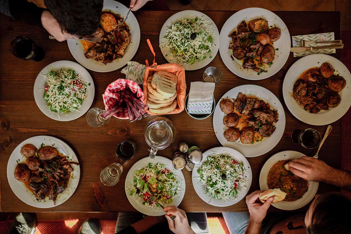 table of food on white plates with several people